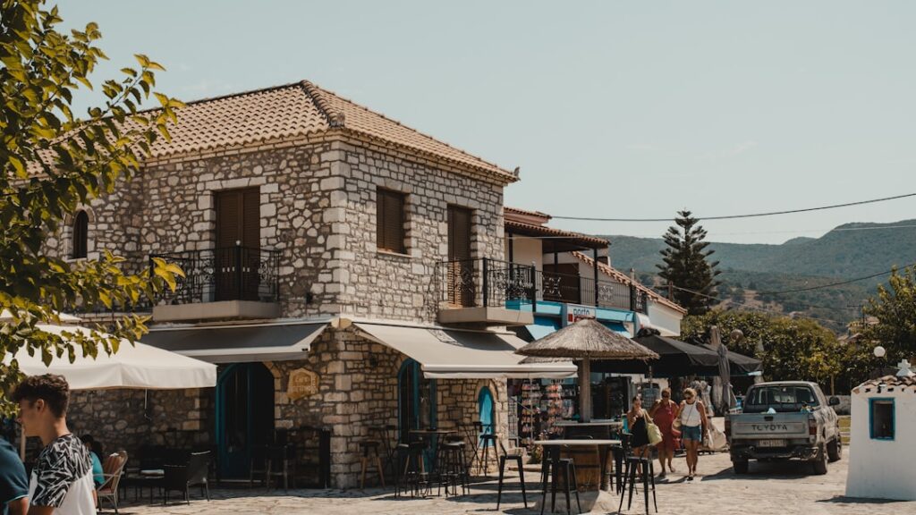 Stenen gebouw met cafés en wandelaars in straat van Mykonos