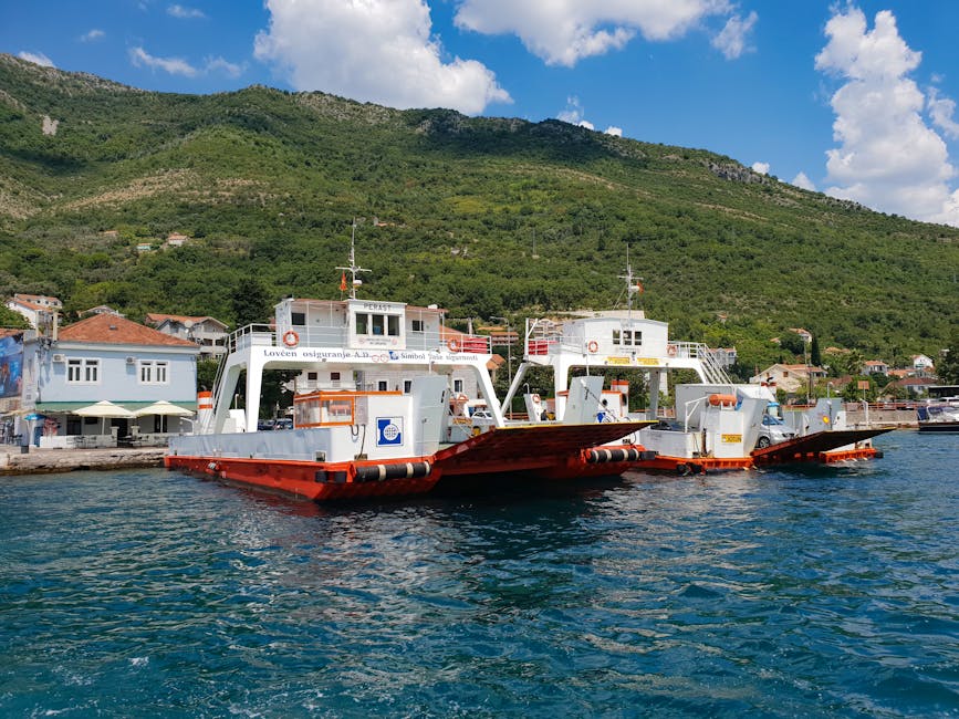 Two red-and-white car ferries docked in calm blue bay with hills