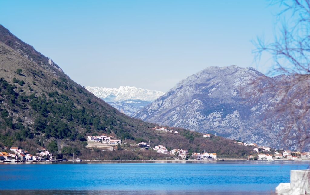 Blue bay and hillside houses near Kotor with rugged mountain backdrop.