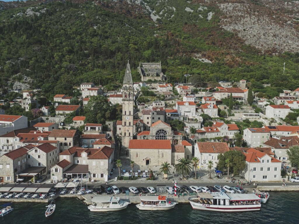 Coastal village with stone church tower and moored boats along waterfront