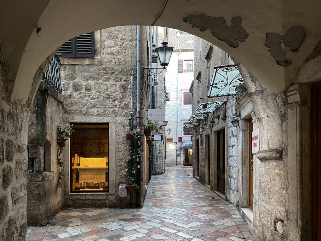Vicoli medievali di Kotor con vetrina illuminata e pavé in pietra