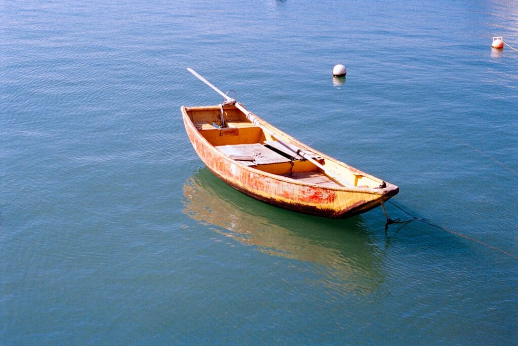 Weathered wooden rowboat tethered in calm turquoise harbor waters