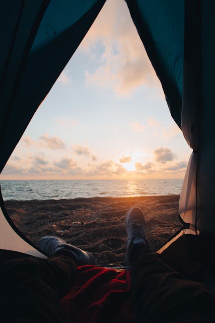 Blick aus Zeltöffnung auf Meer und Sonnenaufgang mit sichtbaren Stiefeln