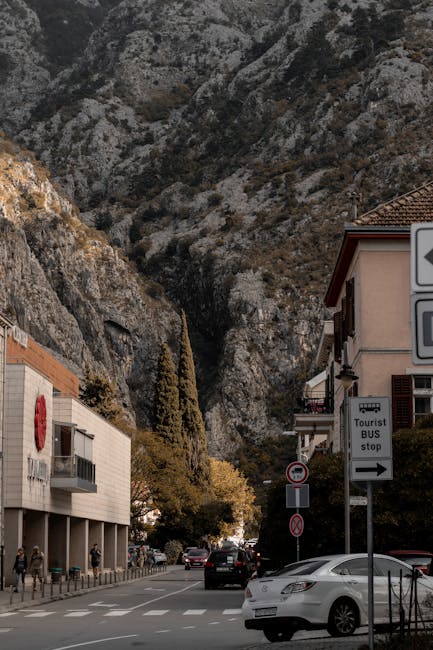 Straße in Kotor mit steilem Felsen im Hintergrund und Verkehr