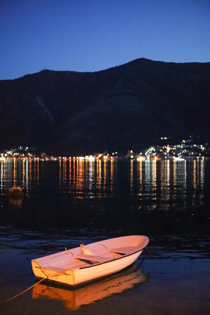 Small white boat moored on Kotor bay with distant lights