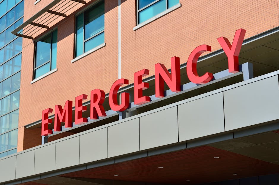 Enseigne rouge 'EMERGENCY' au-dessus de l'entrée d'un hôpital moderne.