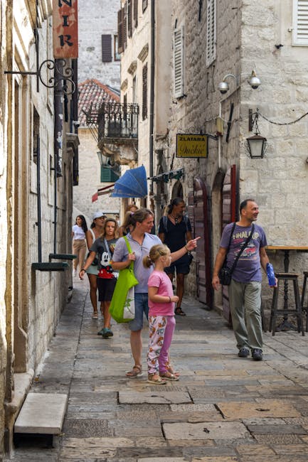 Touristen schlendern durch enge Gasse mit Steinboden in Kotors Altstadt