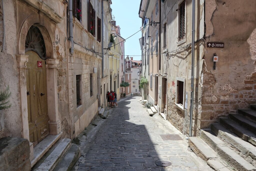 Schmale gepflasterte Gasse zwischen alten Häusern in Kotor mit wenigen Passanten