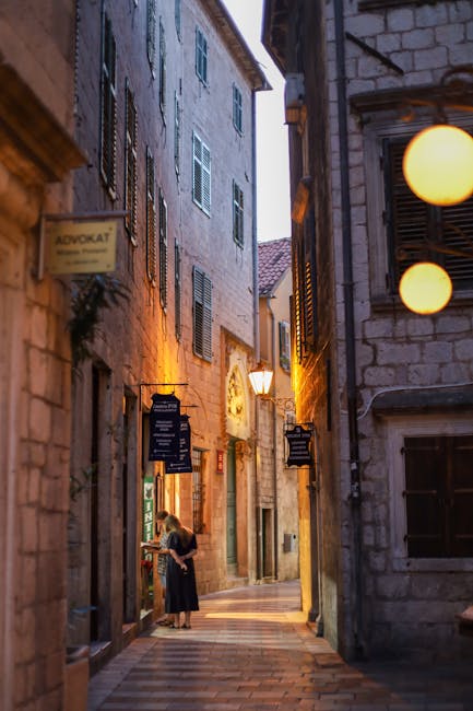 Ruelle éclairée de Kotor avec passante regardant une vitrine.