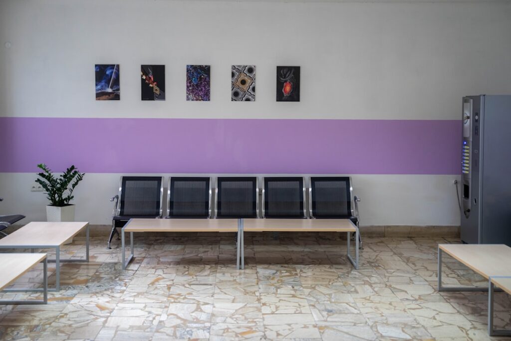 Clinic waiting area with row of metal seats and purple wall stripe