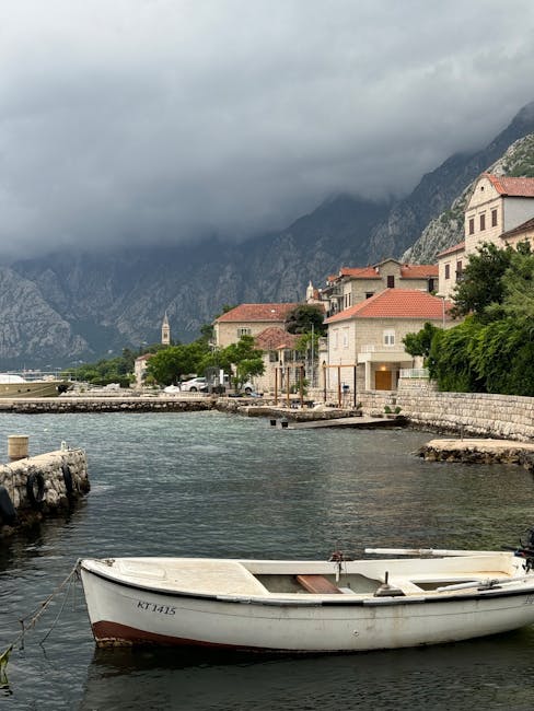 Klein bootje aangemeerd in Kotor-baai voor kust met dreigende wolken