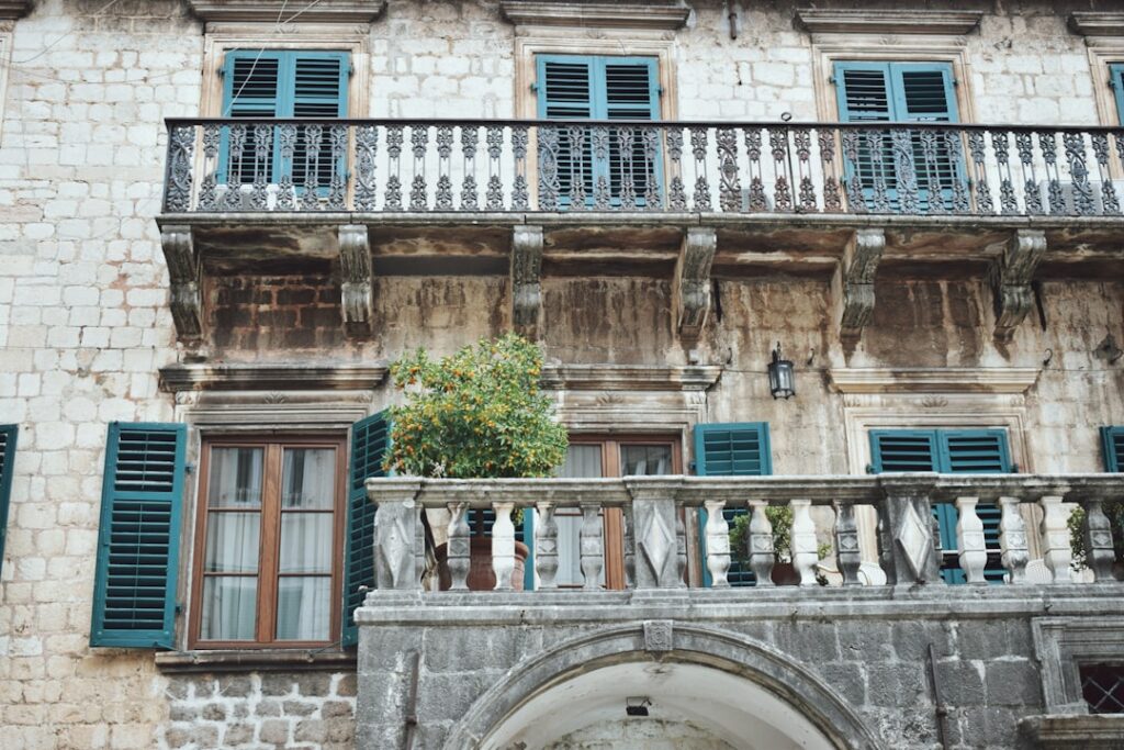 Facciata in pietra con persiane verdi e balconi storici a Kotor
