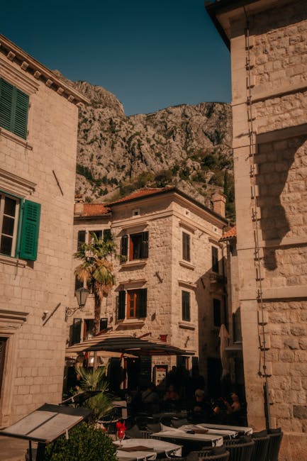 Kleiner Platz mit Cafés und Bergen im Hintergrund in Kotor.