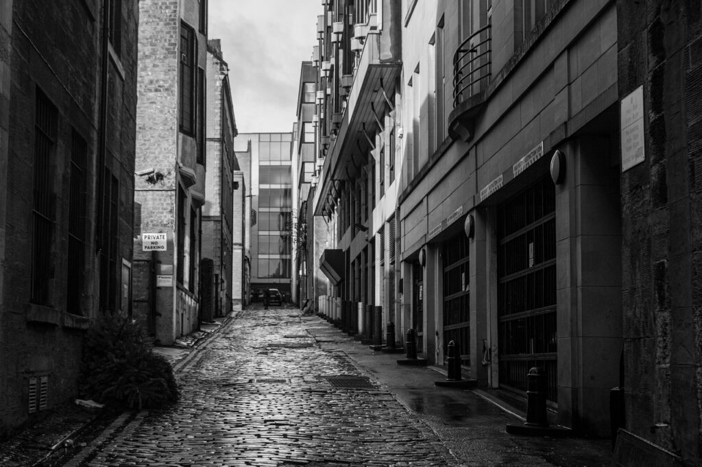 Smal kasseienstraatje met natte stenen tussen hoge gebouwen in Kotor