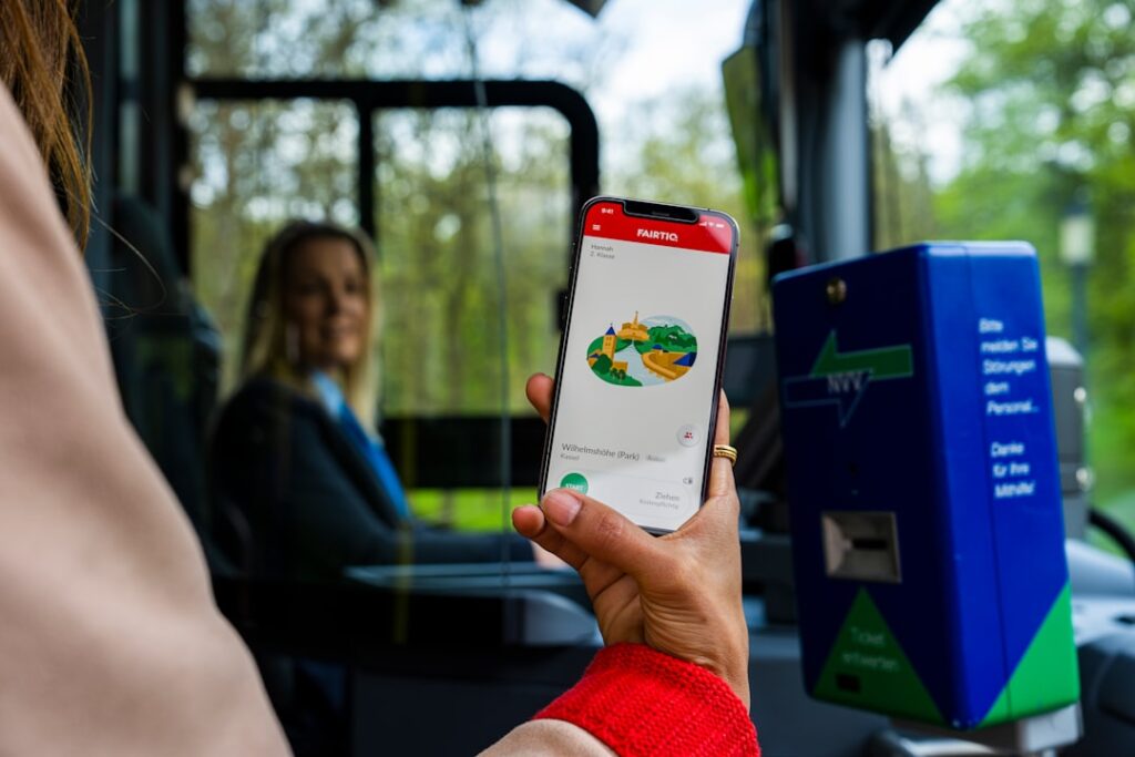 Hand toont mobiel met vervoersapp in bus, chauffeur zichtbaar op achtergrond