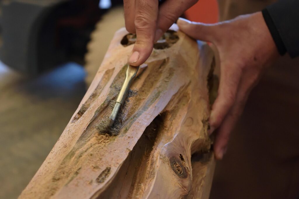 Mani che intagliano legno con scalpello creando venature e dettagli