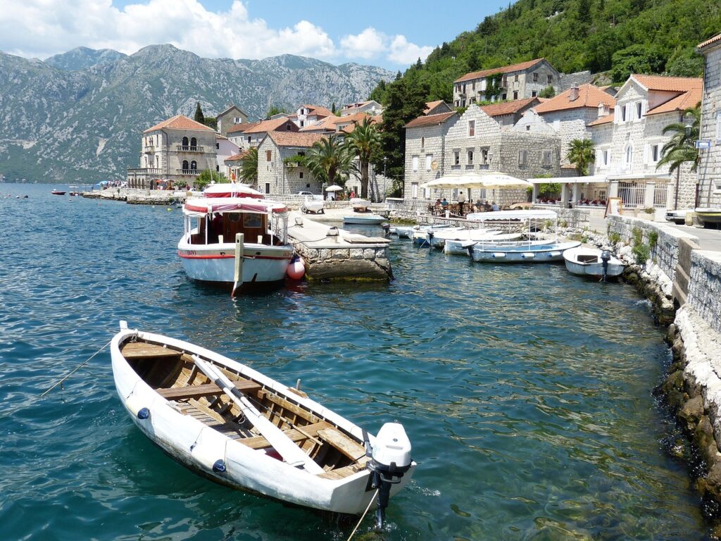 Kleines Ruderboot im Hafen von Kotor vor Steinhäusern.