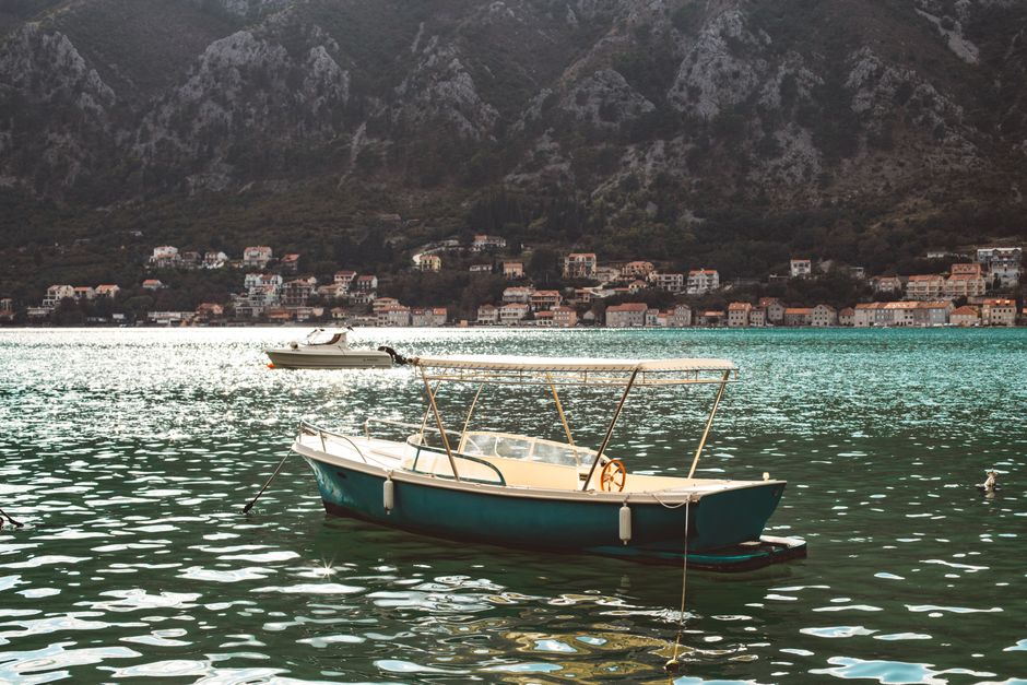 Kleines Boot auf türkisfarbenem Wasser vor Kotor-Bucht.