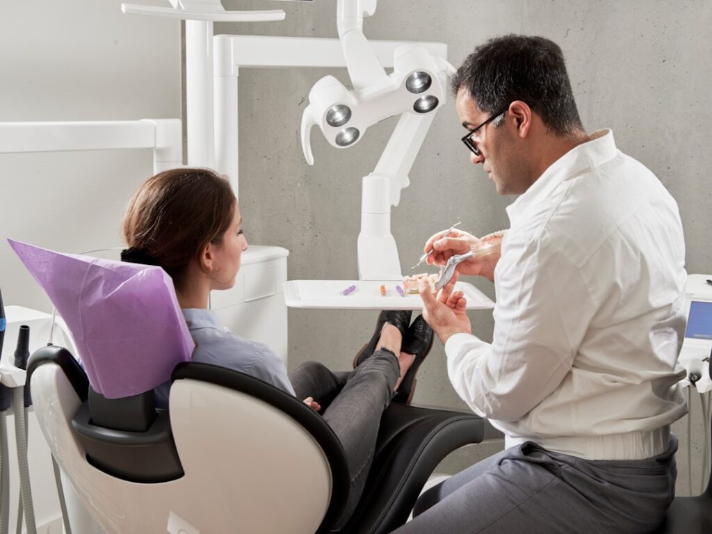 Dentysta wyjaśnia pacjentce model zębów na fotelu stomatologicznym