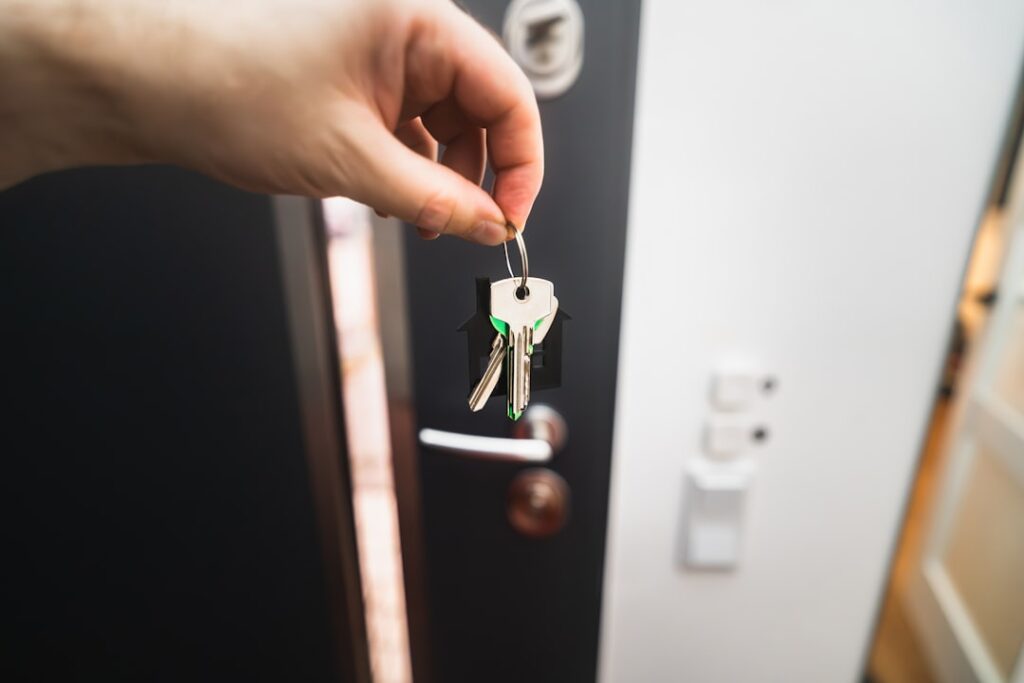 Hands exchanging keys over a rental contract during a keys handover at an apartment door