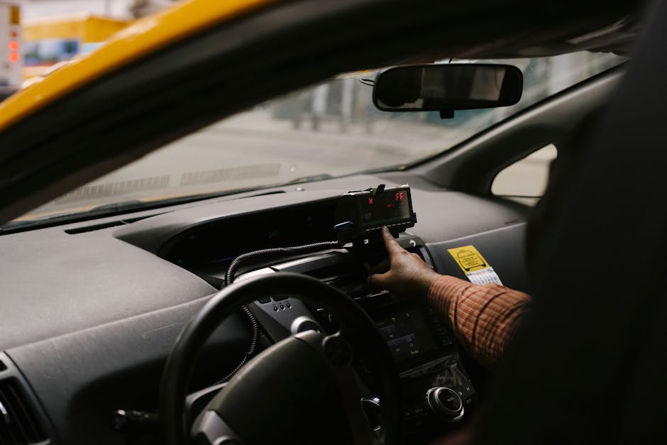 Main du chauffeur réglant un taximètre noir à l'intérieur