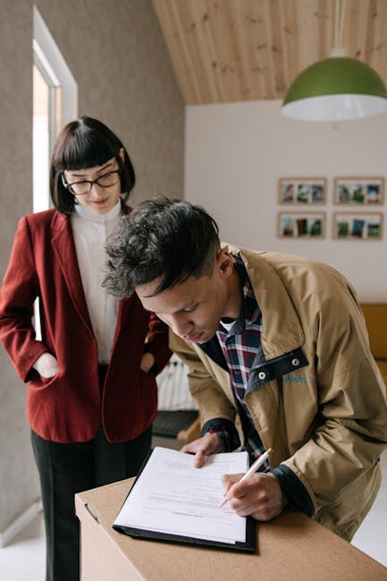 Tenant and landlord signing a rental agreement at a table near an apartment window