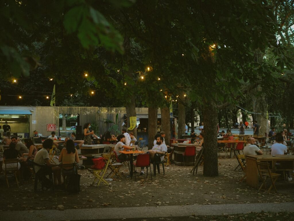 Outdoor beer garden with string lights and people dining in Tirana park
