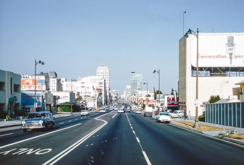 Large avenue urbaine bordée de voitures et de panneaux publicitaires