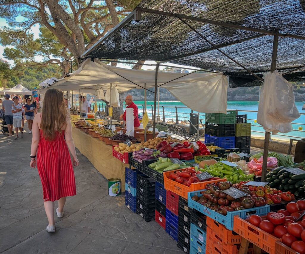 Marché en bord de mer avec stands de légumes et promeneuse