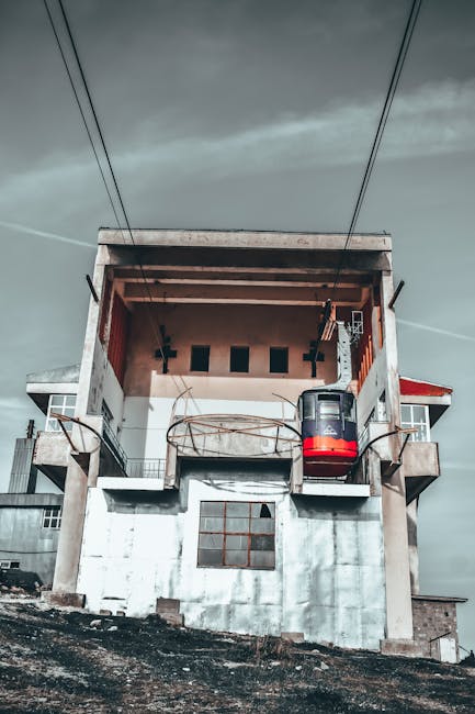 Kabelbaanstation met rood gondeltje omhoog boven betonconstructie in Tirana