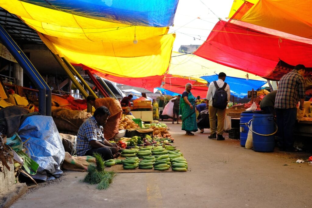 Marché couvert sous bâches colorées avec légumes alignés et vendeurs