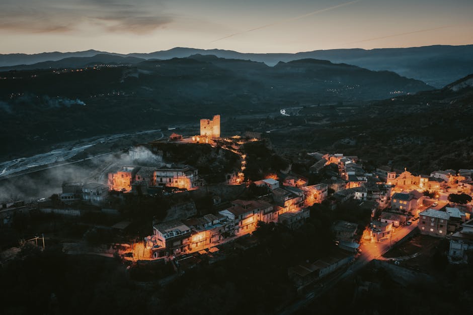 Village rural éclairé au crépuscule avec ancienne tour sur la colline