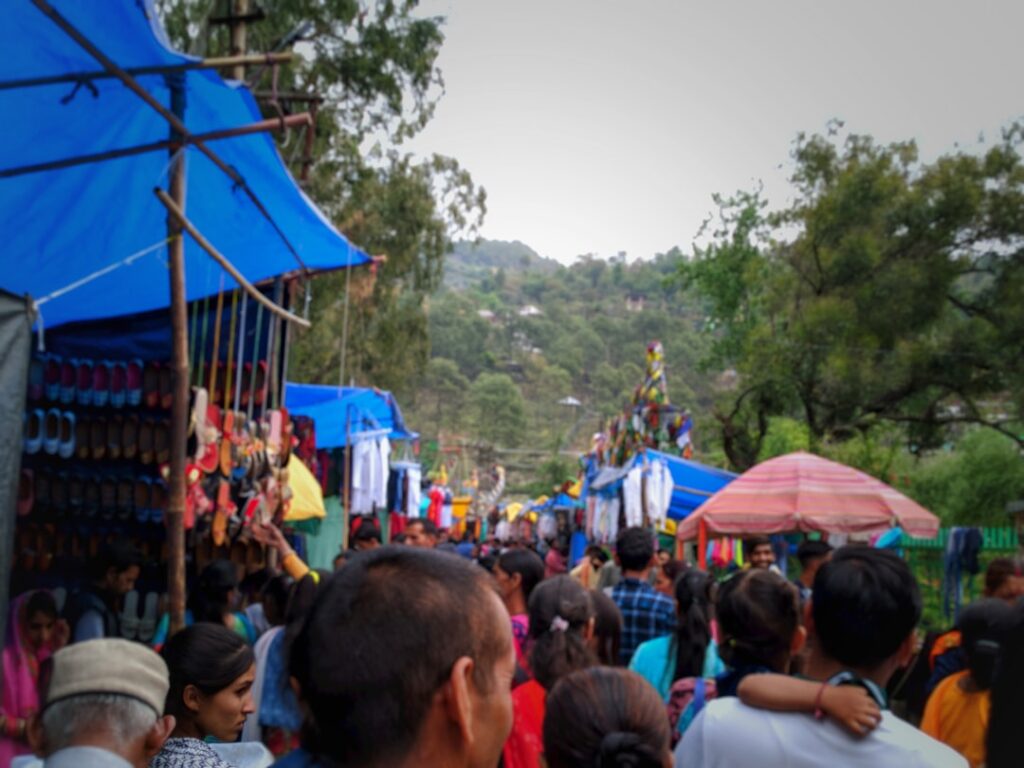 Blue-tarped stalls and dense crowds at an outdoor market near Tirana