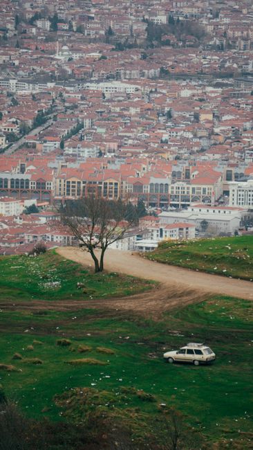 Een eenzame auto op groene heuvel met uitzicht over Tirana