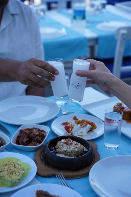 Deux mains trinquent avec des verres de boisson blanche lors d'un repas