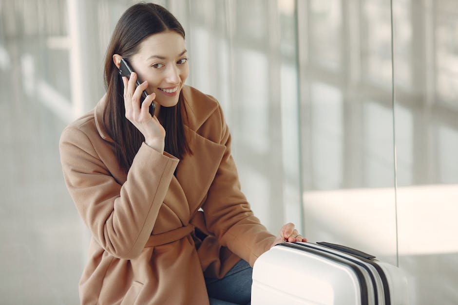 Voyageuse souriante au téléphone assise près d'une valise à l'aéroport du Monténégro