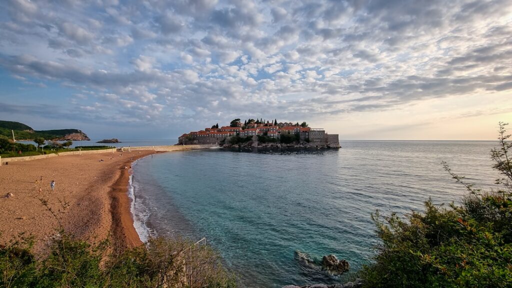 Plage incurvée et l’îlot fortifié de Sveti Stefan au Monténégro