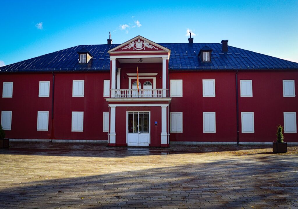 Rotes historisches Gebäude mit weißen Fensterläden auf Platz in Monténégro