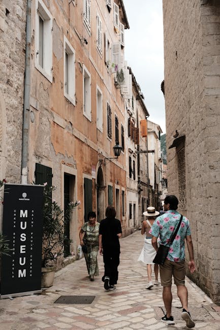 Narrow Kotor alley with museum sign and tourists walking