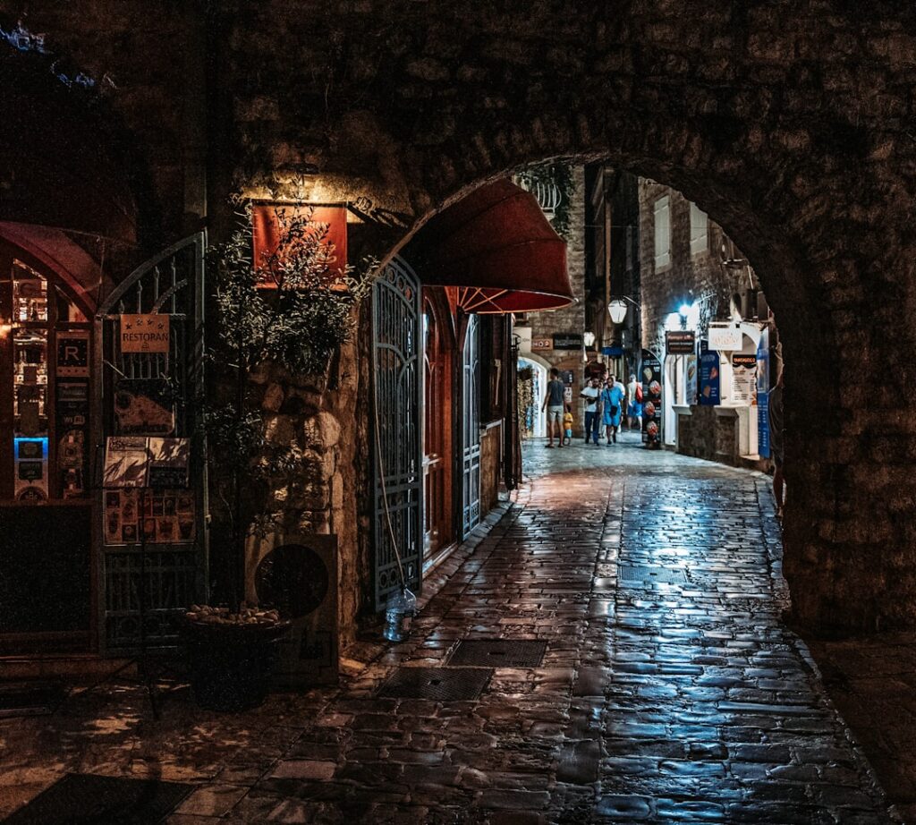 Rue nocturne pavée sous une arche dans la vieille ville de Budva, Monténégro