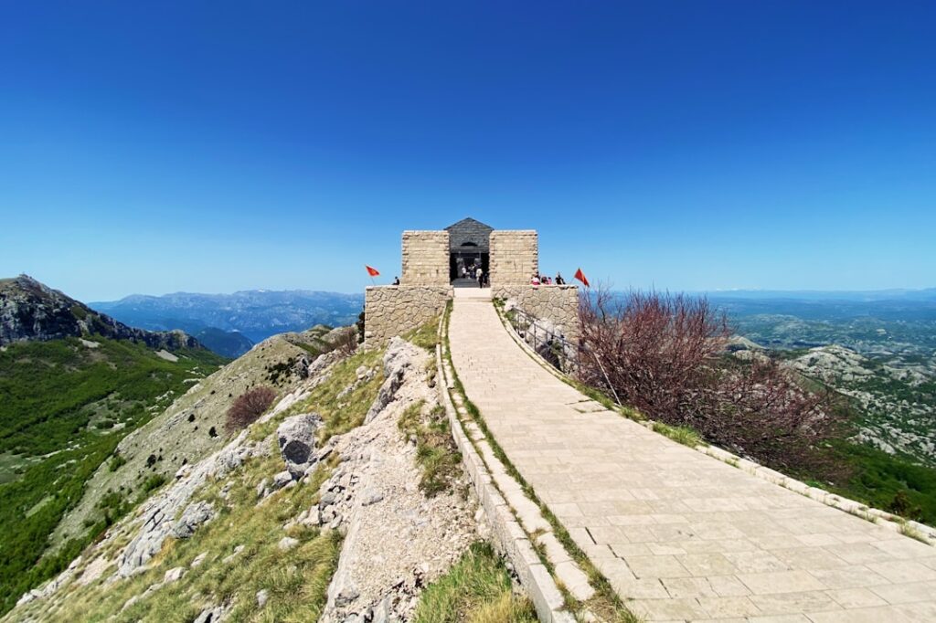 Pflasterweg zum Njegoš-Mausoleum auf dem Lovćen mit montenegrinischen Flaggen