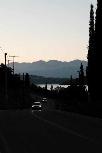 Auto con fari su strada curva al crepuscolo, montagne e mare del Montenegro