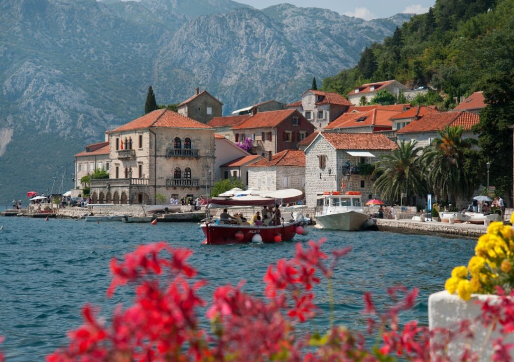 Red-roofed coastal village in Montenegro with boats and vibrant flowers