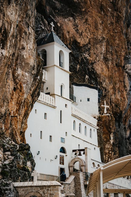 Close-up of white cliffside monastery with bell tower at Ostrog, Montenegro