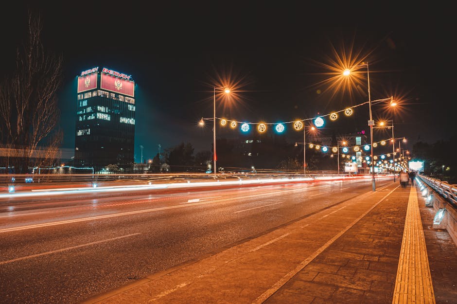 Traînées lumineuses sur avenue de Podgorica, bâtiment éclairé et décorations festives