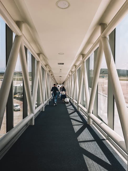Passengers walking down glass jet bridge with luggage at Tivat Airport