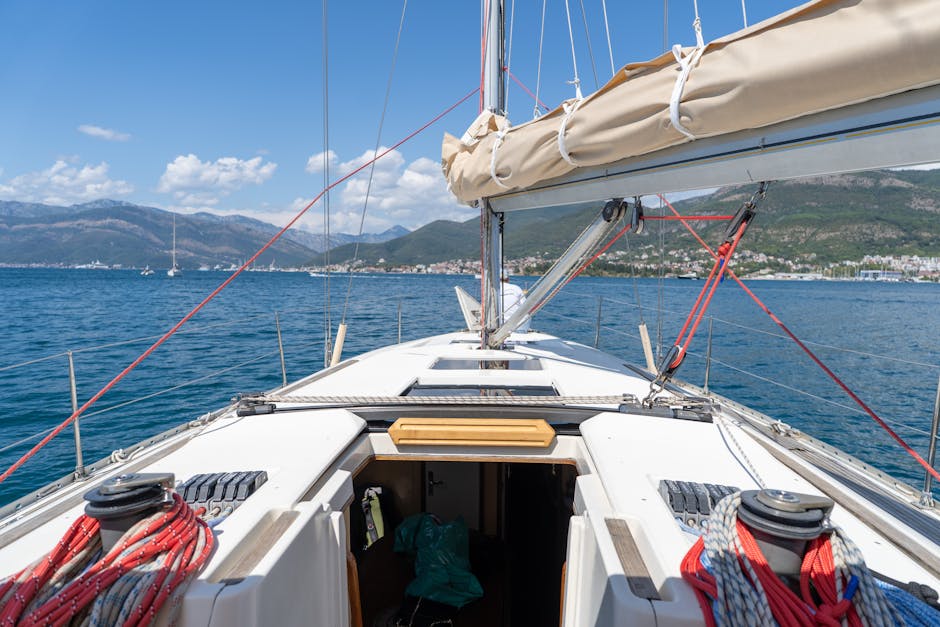 Bow of a sailboat cruising toward Montenegro coastline and distant mountains