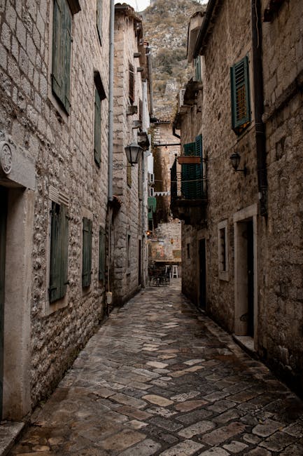 Narrow cobblestone alley with green shutters in Kotor, Montenegro