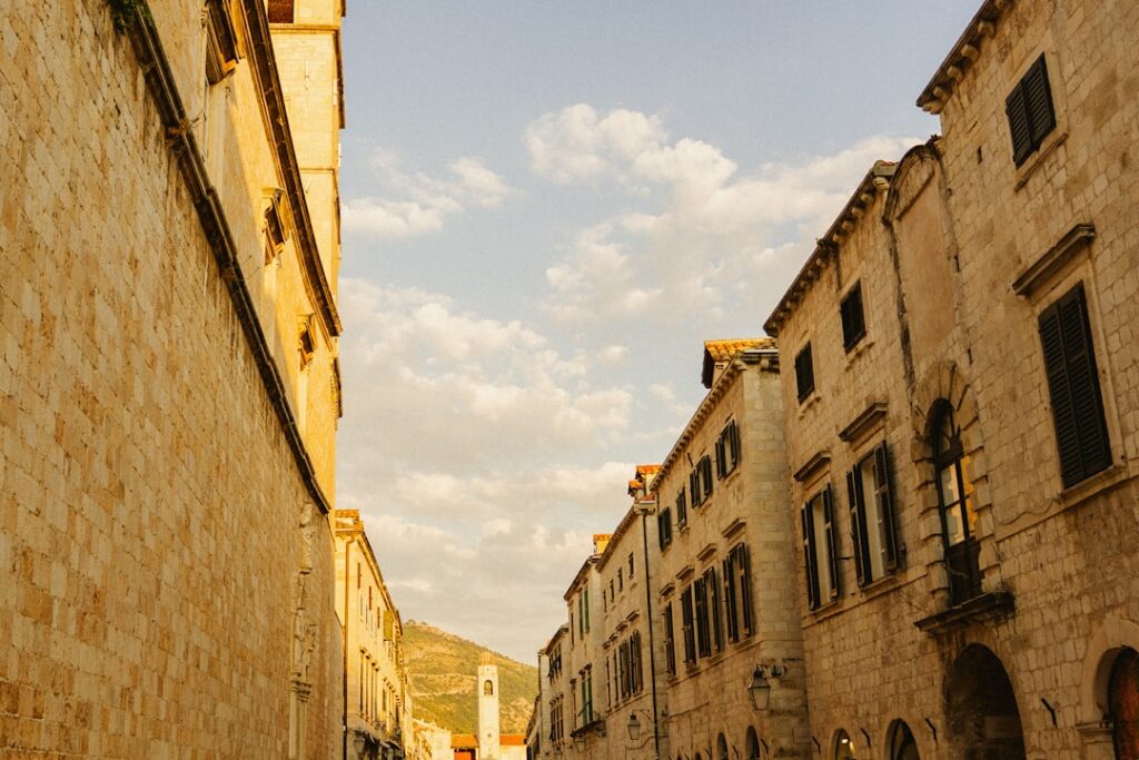 Narrow stone street flanked by historic Kotor walls and distant clock tower