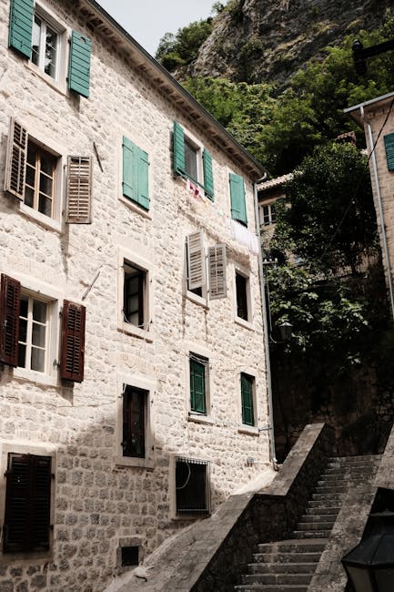 Sunlit stone building with green shutters and stairs in Montenegro's old town